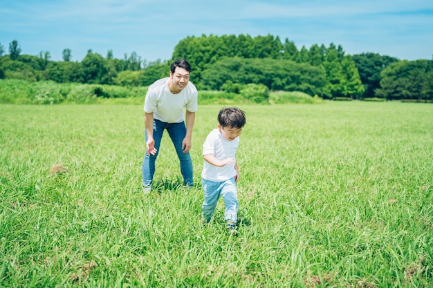 牧草地を走っている少年と見守っている父親