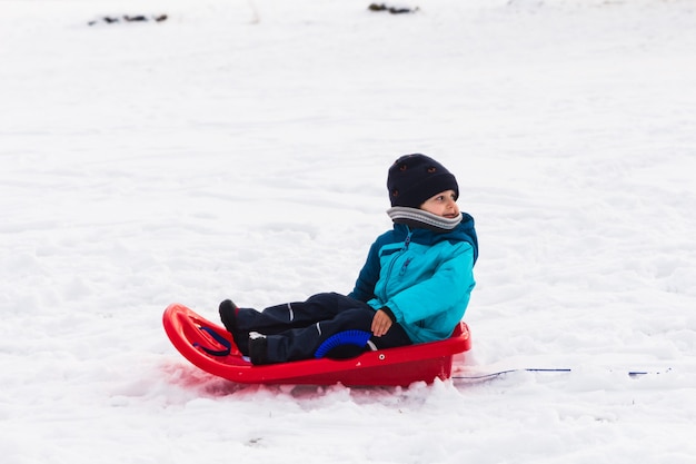 写真 雪の中で赤いそりを持つ少年