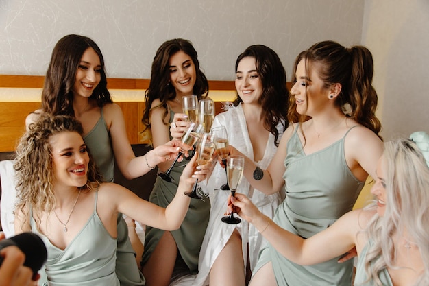 写真 花嫁とブライズメイドは、ベッドの上でシャンパン グラスで乾杯します。
