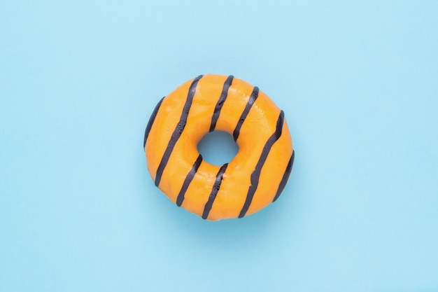 파란색 배경에 밝은 탄산 된 오렌지 도넛. 맛있는 인기 패스트리.
