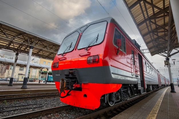 Фото Ярко-красный поезд стоит на платформе железнодорожного вокзала в городе пассажирские перевозки