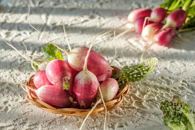 写真 自家製大根の束は、明るい背景の赤と緑のテーブル野菜の上にあります