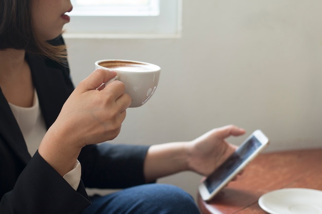 사진 비즈니스 우먼 사무실에서 작업하는 동안 화이트 커피 컵을 들고있다