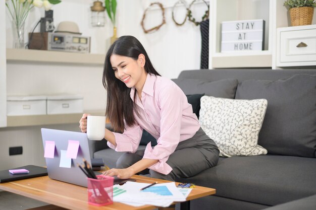 写真 ビジネスの女性はラップトップコンピューターで作業し、リビングルームでビジネスの成長グラフデータを分析して、自宅で仕事をする、ビジネス技術の概念。