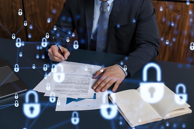 Фото Бизнесмен в формальной одежде подписывает контракт на предотвращение вероятности рисков в области кибербезопасности значки голограммы padlock над рабочим столом