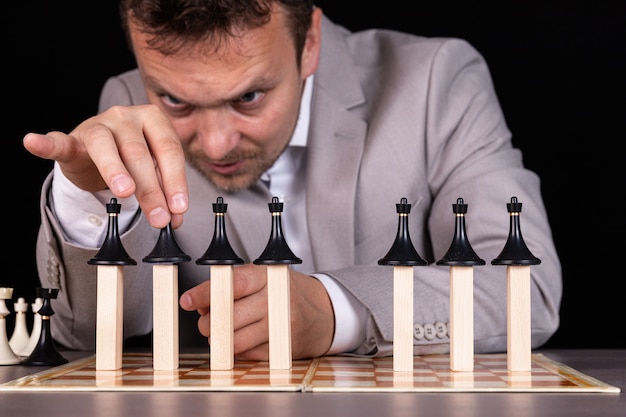 Фото Бизнесмен строит пирамиду из шахматных фигур и деревянных блоков