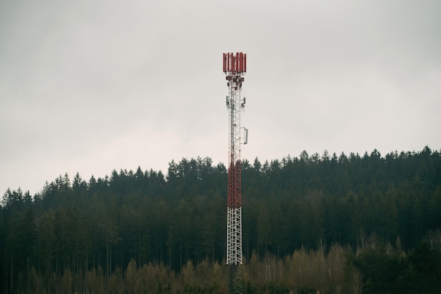 Фото Вышка сотовой связи в поле с деревьями на заднем плане