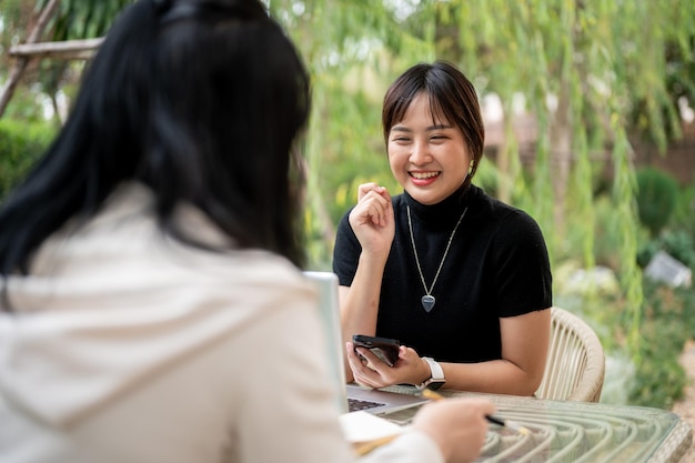 写真 庭で遠隔作業をしている友人と話している陽気なアジア人女性