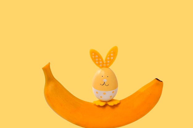 Фото Веселый пасхальный кролик сидит на спелом банане желтый праздничный фон