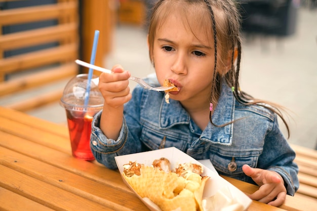 Фото Ребенок кусает твердую пищу, сидя за столиком в городском кафе на улице