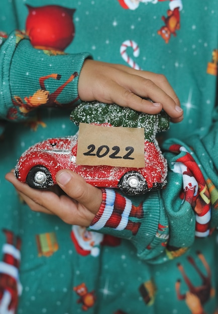 写真 子供は2022年と新しいおもちゃの夢で彼の手に新年の車を持っています