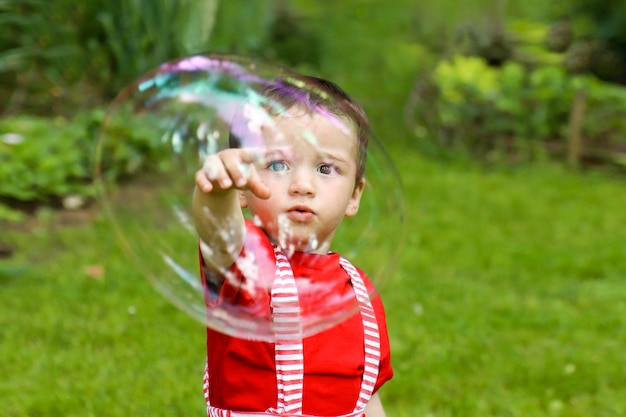 写真 子供は夏に自然の中でシャボン玉で遊ぶ