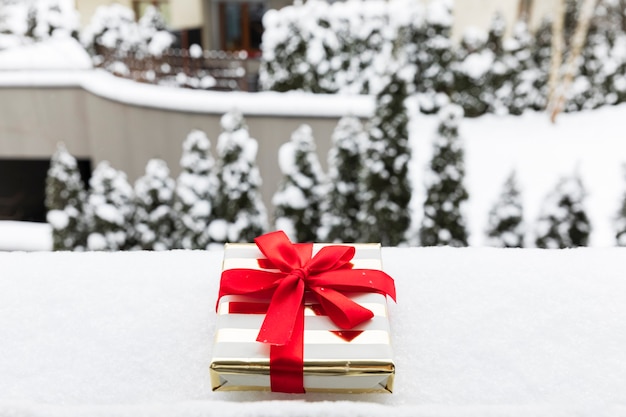 写真 雪の上のお祝いパッケージのクリスマスプレゼント。 c