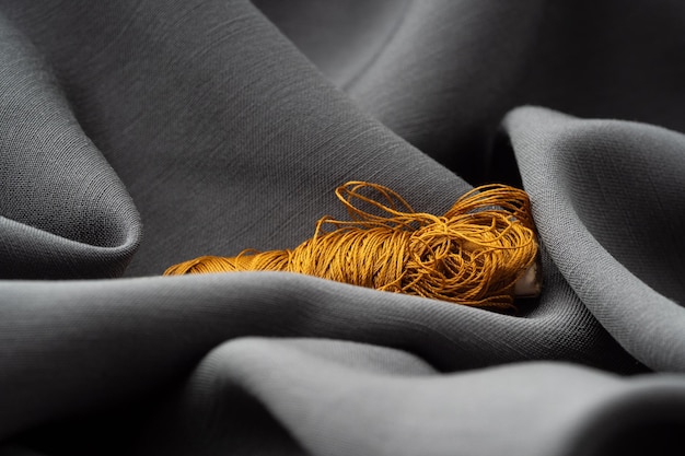 Фото Катушка с медными нитями в драпированной мягкой серой ткани крупный план макро ателье пошив швейный фон текстура шелковых нитей и сатенной ткани концепция высокой моды дизайнера моды
