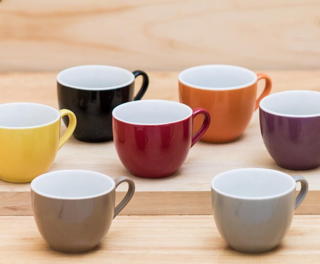 写真 さまざまな色のカップのコレクションが木製のテーブルの上にあります。