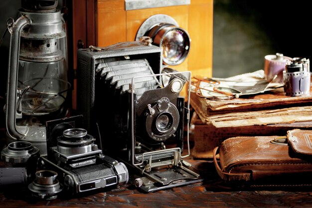 Фото Коллекция старых фотоаппаратов и кожаный чехол на столе.