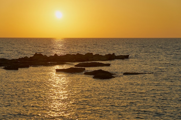 写真 岩の多い地中海沿岸の色とりどりの夕日