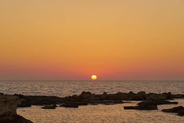 写真 岩の多い地中海沿岸の色とりどりの夕日