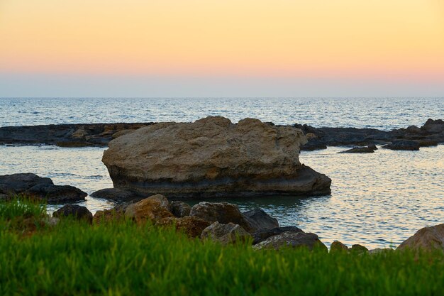 写真 岩の多い地中海沿岸の色とりどりの夕日