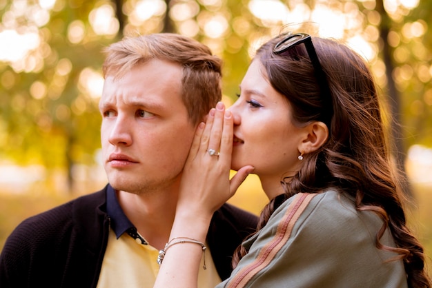 Фото Пара молодой мужчина и женщина рассказывают друг другу тайну, шепчут на ухо