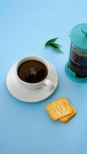 写真 水差しとティーポットのミルクティーと一緒に黒い熱いお茶のカップは、太陽光線のある青いテーブルの上に立っています上からの眺め