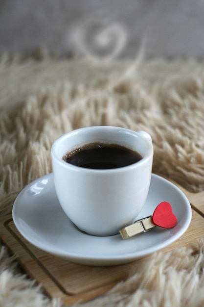 Фото Чашка черного крепкого кофе стоит на деревянной доске на мягком одеяле завтрак