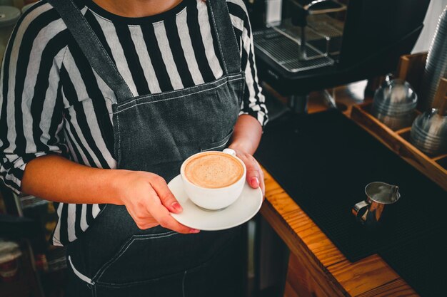 写真 一杯のコーヒー カプチーノ メニューをコーヒー ショップで手に女性バリスタを提供する準備ができて