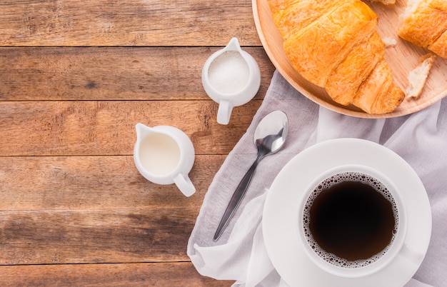 写真 木製のテーブル、トップビューでミルク、砂糖、クロワッサンのパンとコーヒーのカップ