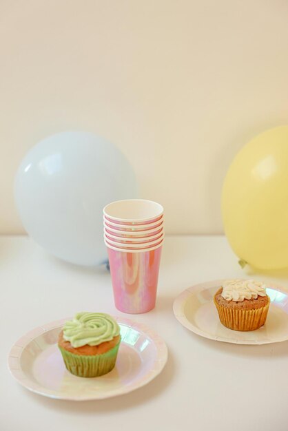사진 컵케이크와 컵이 테이블 위에 풍선이 있습니다.