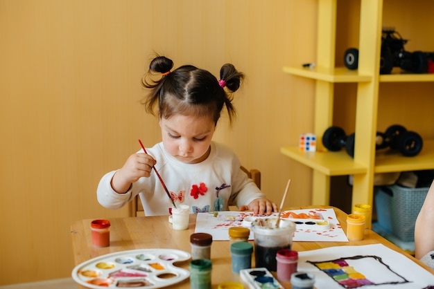 Фото Милая маленькая девочка играет и рисует в своей комнате. отдых и развлечения.