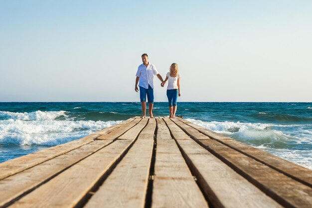 A De man en het meisje lopen langs de pier bij de zee in de natuurreis