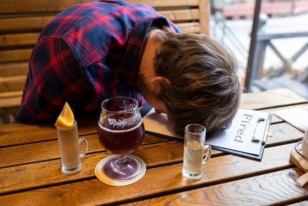 Фото Депрессивный мужчина в баре борется с алкогольной зависимостью. человек, потерявший работу
