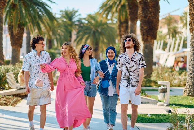 Фото Разнообразная группа туристов, одетых в летнюю одежду, прогуливается по туристическому городу с широкими