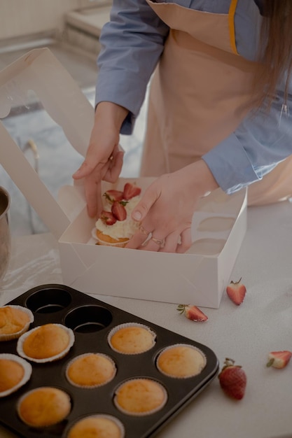 사진 여성 페이스트리 셰프 는 가정 에서 만든 케이크 를 전시 하는 고객 들 에게 배송 하기 위해 컵케이크 를 패키지 로 포장 한다