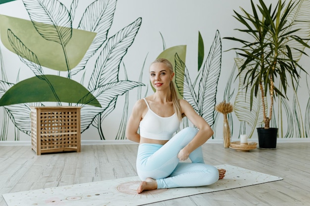 Фото Подходящая женщина-инструктор тренируется на коврике для йоги в яркой студии