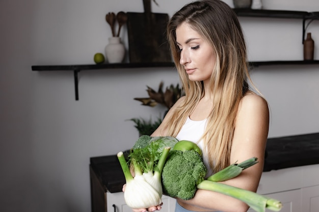 写真 フィットネスの女性は新鮮な生の緑の野菜でいっぱいを保持します