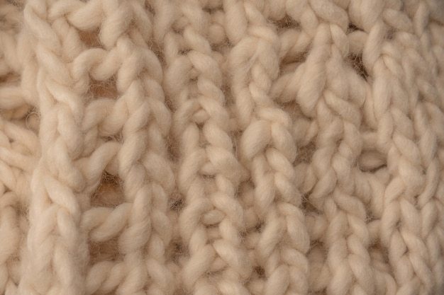 Фото Фрагмент бежевого трикотажа, связанного из белой овечьей шерсти