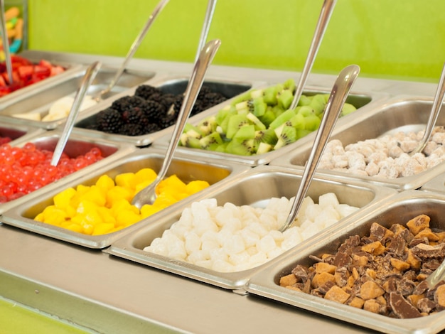 âfrozen yogurt toppings bar. yogurt toppings ranging from fresh fruits, nuts, fresh-cut candies, syrups and sprinkles.