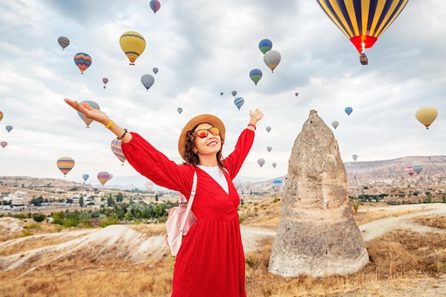 Фото Девушка в платье поглощена захватывающим дух зрелищем полета воздушных шаров в каппадокии, раю для путешественников.