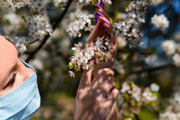 개화 정원 사이에서 봄에 보호 의료 마스크에 소녀. . 봄 알레르기 개념