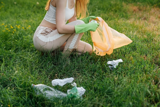 해질녘 공원에 있는 한 소녀가 공원에서 쓰레기 수거에 참여하고 있습니다. 환경 관리 폐기물 재활용 쓰레기 분류