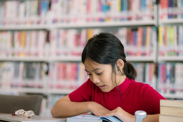 写真 女の子が図書館のテーブルに座って本を読んでいる