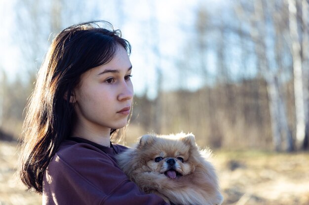 写真 女の子が公園で犬と歩きペットと一緒に屋外レクリエーション小さな子犬と一緒に肖像画を描いています