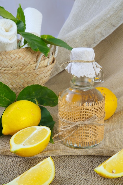 Фото Стеклянная бутылка лимонного уксуса. свежие лимоны на заднем плане