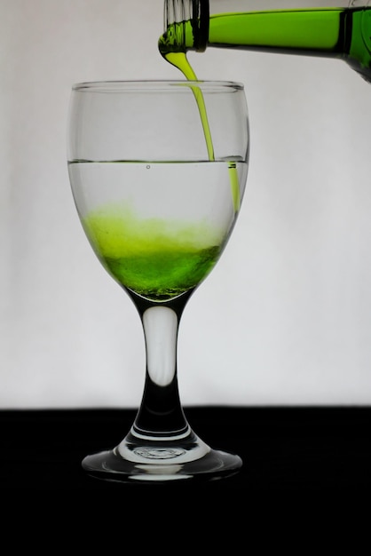 Фото Стакан, заполненный зеленой водой на белом фоне