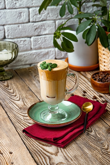Фото Стакан кофе с молоком, украшенный листьями мяты на столе, кофе далгона, вертикальное фото.