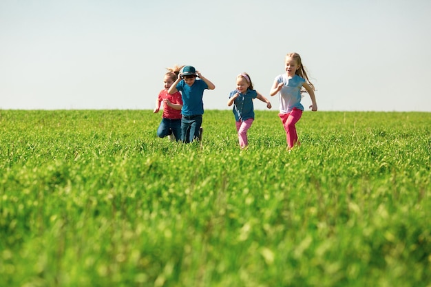 写真 男の子と女の子の幸せな子供たちのグループは、晴れた夏の日に芝生の上の公園で実行されます民族の友情平和優しさの子供時代の概念