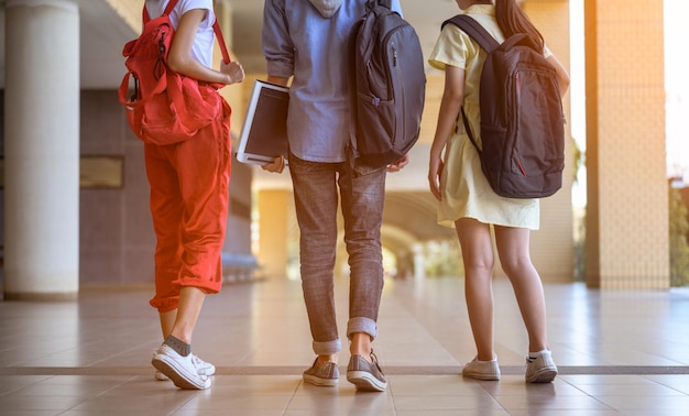 写真 学生のグループが学校に歩いています。生徒はバッグを持ち、学校の備品を持っています。