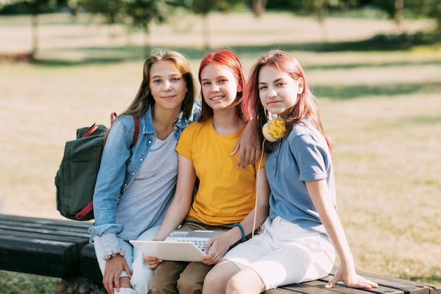 写真 十代の女の子のグループが公園のベンチに座って一緒に授業の準備をしています