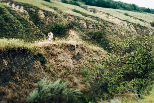 地球の侵食の緑の峡谷の背景に明るい服を着た女の子と男